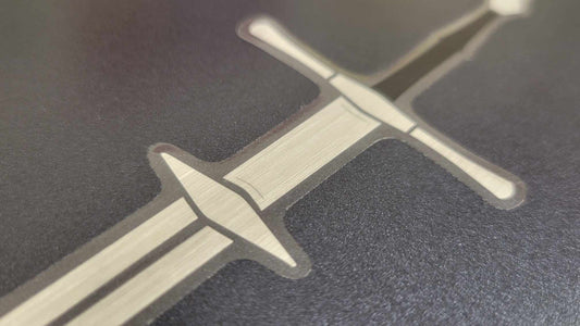 Zweihander sword vinyl sticker by InkBird Print Studio, metallic silver and black foil, detailed blade, adhesive backing, on matte backdrop.