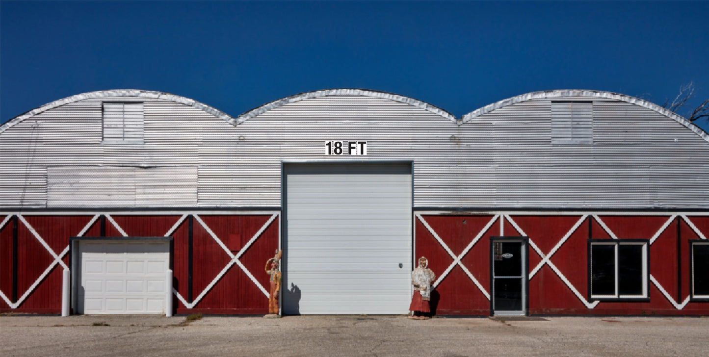 Red and silver metal commercial building with 18 FT white vinyl garage door, standing seam panels, and a bold industrial design.