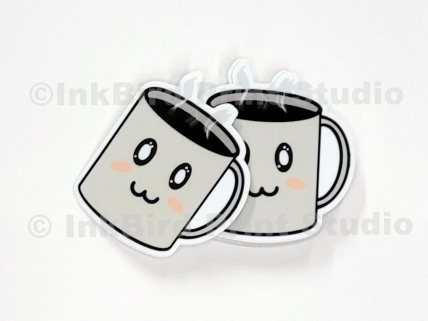 Vinyl coffee cup sticker by InkBird Print Studio with two cartoon mugs, rosy cheeks, clinking, and steamy details; die-cut, adhesive-backed.